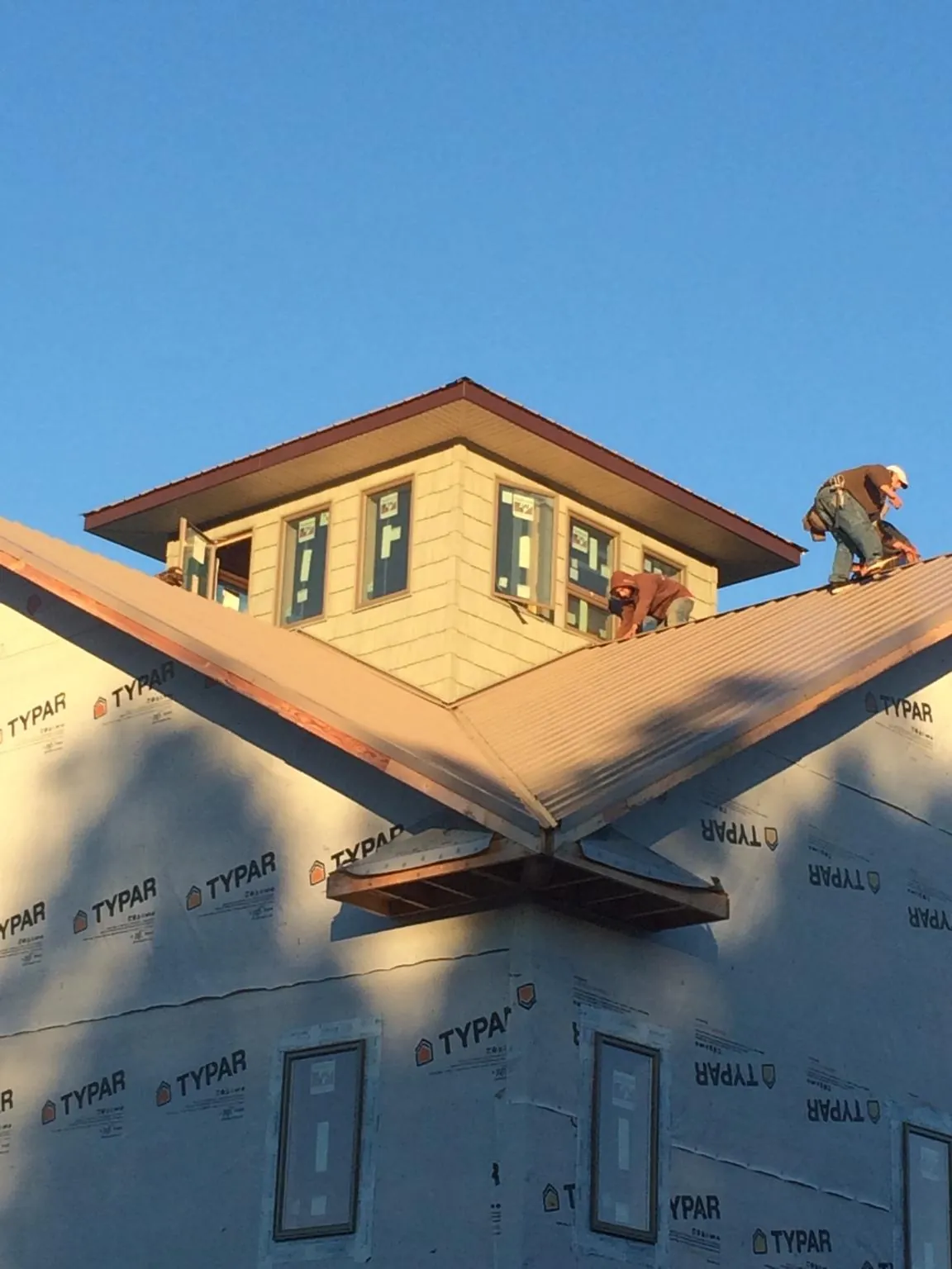 Roofers working around a rooftop cupola on a new metal roof at sunset — Roof Waterproofing in Carrollton by Roofing Brothers
